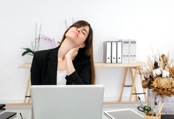Business woman suffering neck pain in her office