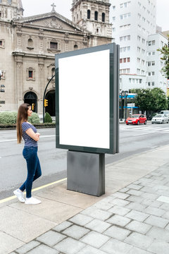 Young woman looking at a billboard in the city
