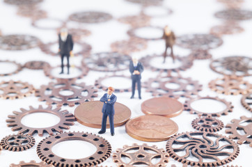 Conceptual photo of gears, coins and toy people. Business, law or political concept, which could represent decision making, leadership, teamwork  and so on. Selective focus.