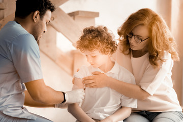 Obraz premium I hold it. Serious practitioner siting in semi position and wearing sterile gloves while dressing right arm