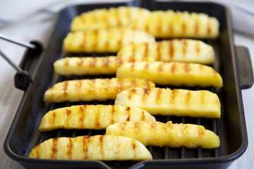 Grilled pineapple slices in grilling pan, side view. Summer food. Close-up. Selective focus.