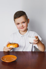 A boy, a kitchen, a bagel and milk. Healthy breakfast.