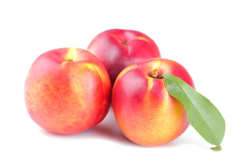 A large ripe fresh nectarine with a leaf on a white isolated background