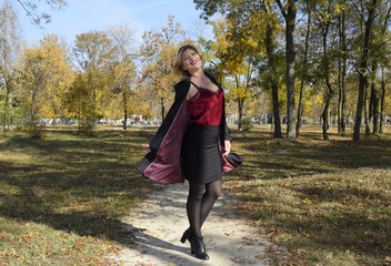 A woman is posing in front of a camera in an autumn park. autumn photo shoot. Autumn in the park.