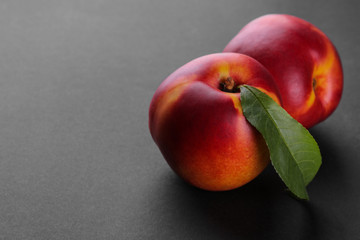 Ripe large nectarines with a green leaf close-up on a black background with a place for an inscription