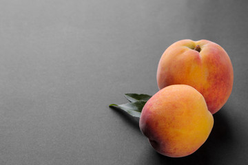 Ripe large peaches with a green leaf close-up on a black background with a place for an inscription
