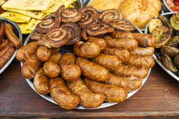 fried sausages on an open fire on a metal plate stand on a wooden table