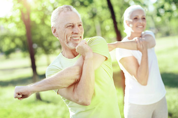 Training together. Productive useful exercises for two cheerful active senior people