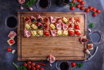 Wooden board with pinxtos or tapas with jamon, ham and sausage, flat lay