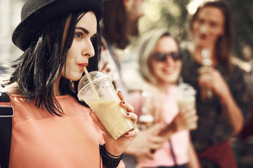 Side view pensive girl drinking delicious cocktail while having fun with friends