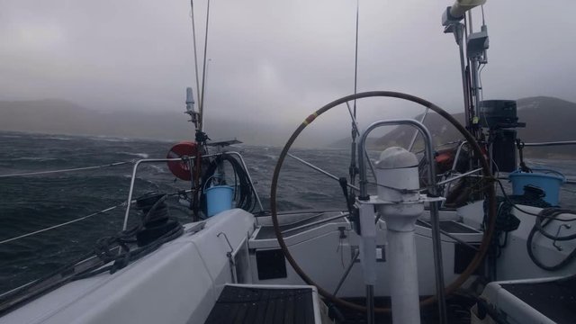 View from board yacht sailing on stormy sea waves. Sail boat swinging on waves