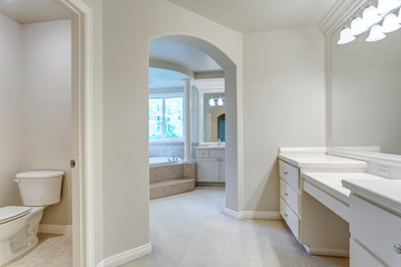 Elegant master bathroom with makeup vanity and arched doorway.