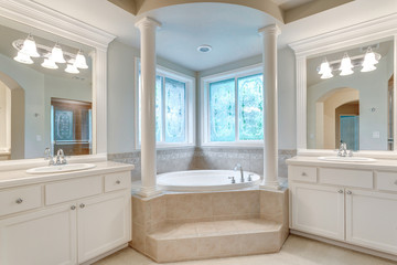 Luxury master bathroom with corner tub under stained-glass windows.