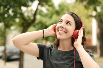 Portrait of young beautiful woman with red headphones listening