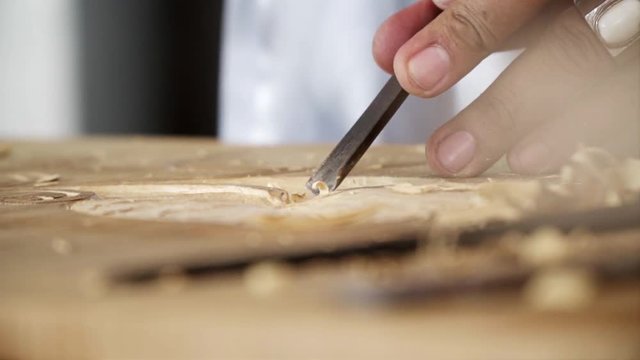 A SLOW MOTION CLOSE UP SHOT of a chisel carving on a piece of wood
