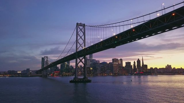 Aerial cityscape flythrough video of the Bay Bridge and San Francisco skyline with colorful sunset