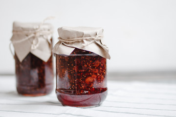 glass jars with raspberry jam on a wooden table, home-made preparations, cooking, homemade desserts