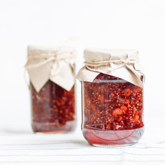 glass jars with raspberry jam on a wooden table, home-made preparations, cooking, homemade desserts
