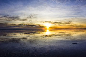 Fototapeta na wymiar Uyuni reflections are one of the most amazing things that a photographer can see. Here we can see how the sunrise over an infinite horizon with the Uyuni salt flats making a wonderful mirror. 