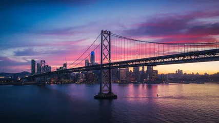 Fotobehang Luchtfoto stadsgezicht van San Francisco en de Bay Bridge met kleurrijke zonsondergang © heyengel