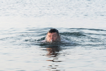 A young man jumps out from under the water with splashes