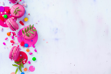 Macaroon cookies on a colorful background with confetti. Vibrant party concept with copy space. Pink and purple palette flat lay.