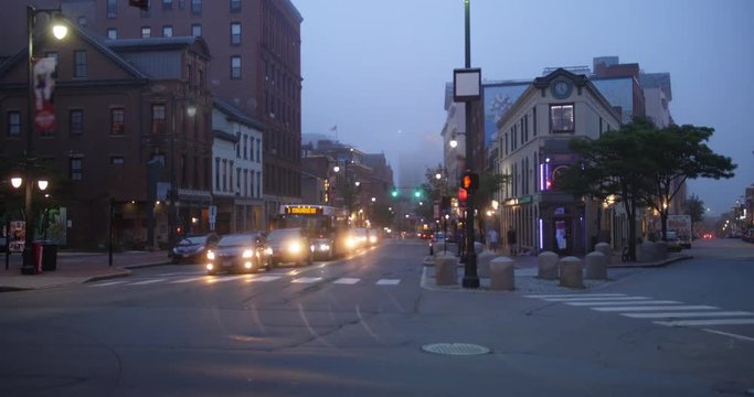 A night time lapse view of downtown traffic and businesses along Congress Street in Portland, Maine on a foggy evening.  	