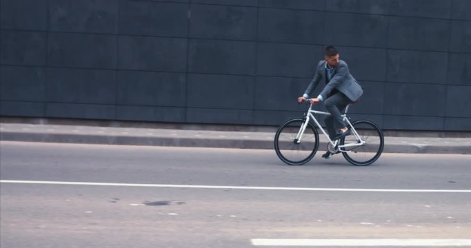 TRACKING Handsome young adult man wearing suit riding his classic bicycle to work in the morning. 4K UHD 60 FPS SLOW MOTION