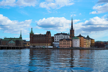 Old city of Stockholm with reflections in water under the blue cloudy sky. 