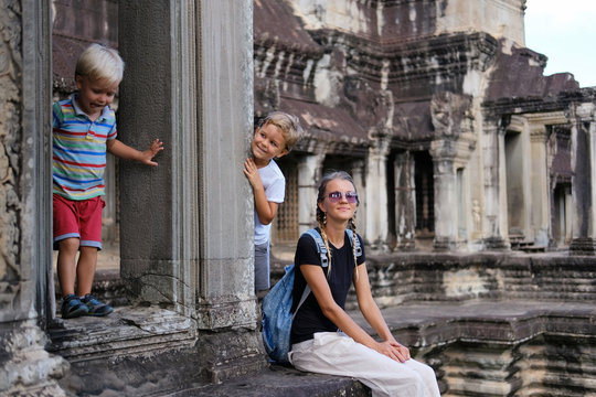 Happy tourists family, mother and two children in Angkor temple site, Cambodia. Concept travel, discovery, family