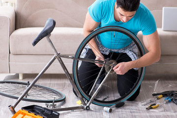 Obraz premium Young man repairing bicycle at home