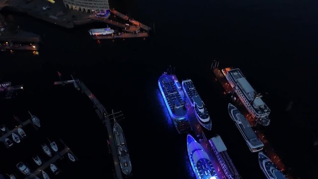 Aerial view of waterfront night illuminated view of Port of Hamburg, Germany. Downtown district city roads buildings office skyscrapers ferry terminal. Iluminated ships with blue lights at Elbe river.