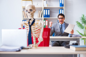 Businessman working with skeleton in office