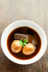 Eggs and pork boiled in the gravy on wooden table, Thai food.