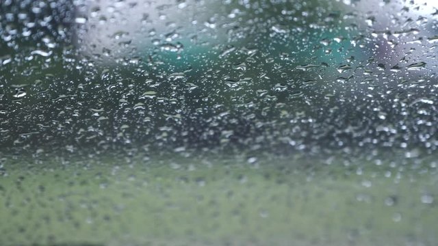 Raindrops outside the window with green nature background 