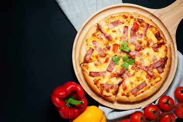 Delicious Italian pizza sliced ham, bacon and cheese with food ingredients on old kitchen table.