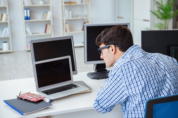 Businessman sitting in front of many screens