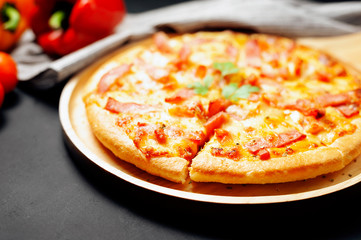 Delicious Italian pizza sliced ham, bacon and cheese with food ingredients on old kitchen table.