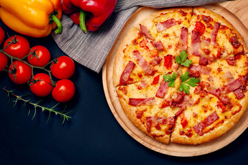 Delicious Italian pizza sliced ham, bacon and cheese with food ingredients on old kitchen table.