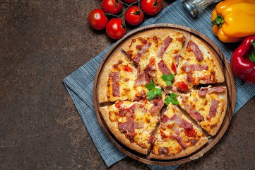 Delicious Italian pizza sliced ham, bacon and cheese with food ingredients on old kitchen table.