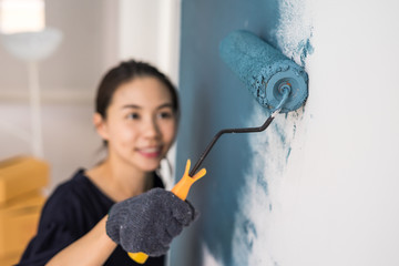 Young asian happy woman painting interior wall