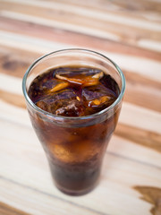 Drink cola with ice in glass on wooden table