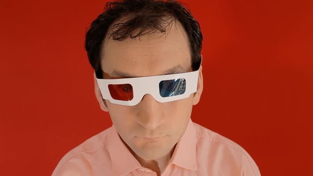 A funny ugly man, wearing disposable 3d stereo glasses, getting sexually aroused by what he's looking at, trying to touch it while putting out his toungue.

