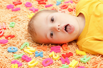 Happy kid in colored clothes playing with plastic letters. Learning the alphabet, preparing for school.