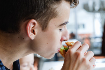 Boy eating Hamburger and french fries in plate on table, bitten off