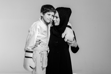 Happy Muslim mom with little son in kimono hugging after competition.