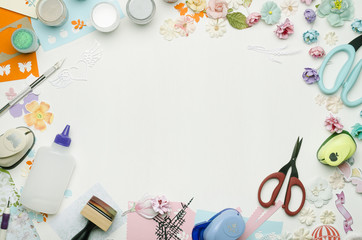 Empty white space in the center surrounded by paper flowers, multi-colored paper and scrapbooking materials. Top view
