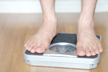 Legs of men standing on scales weight. Concept of health and weight loss.