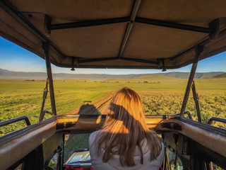 Woman standing in jeep, looking out while Driving in the Serengeti National Park, Tanzania