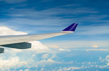 Fototapeta premium Wing of airplane flying over the cloudy sky.